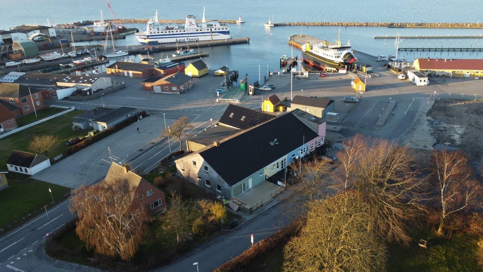 Søby Havn i dagslys med færge, kaj og byens huse set fra luften