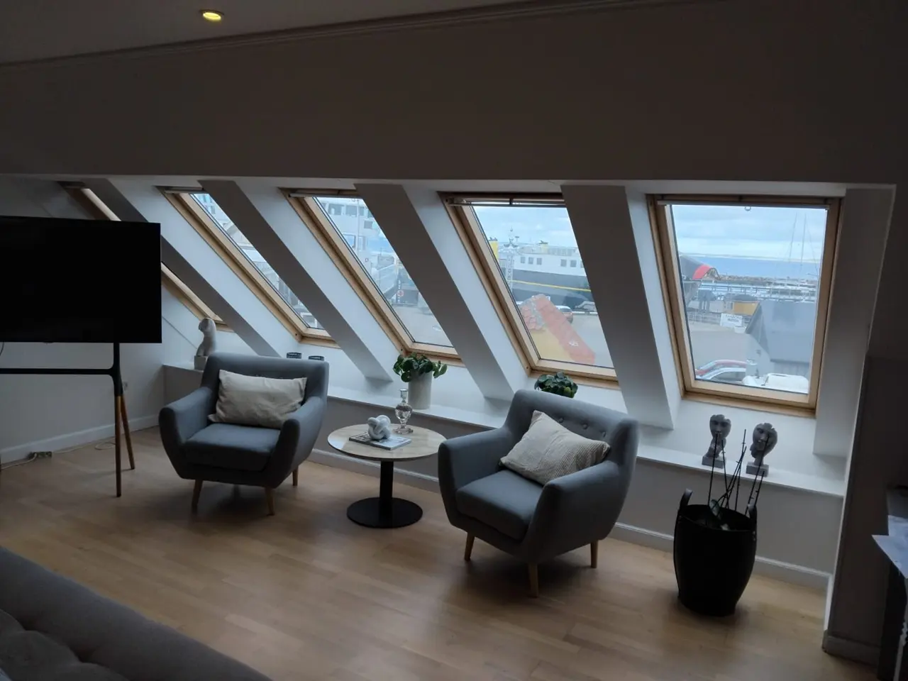 Lys loftsstue med række af ovenlysvinduer og udsigt over Søby Havn og færgen