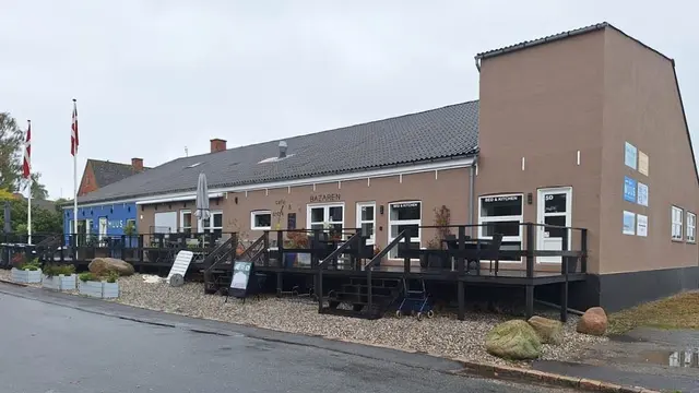 Terrassen — Bygningens facade med husets skilt og træterrasse langs husets forside
