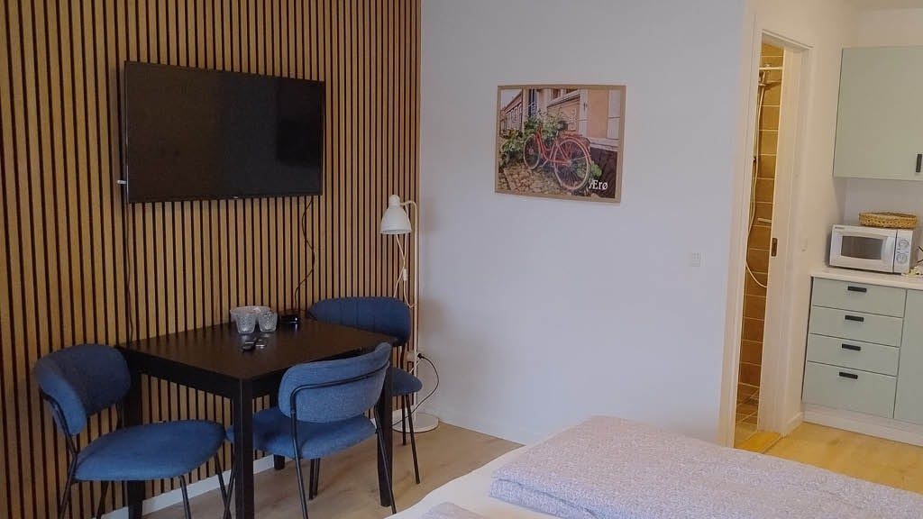 Spiseplads med bord til fire, fladskærm og trælamelvæg